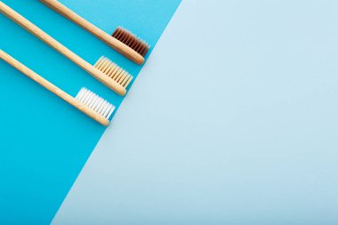Mavi arka plan üst görünümünde çevre dostu bambu diş fırçası ile diş bakımı. Sıfır atık ve plastiksiz konsept.