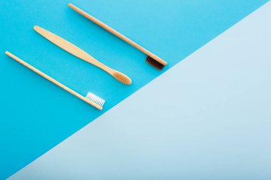 Mavi arka plan üst görünümünde çevre dostu bambu diş fırçası ile diş bakımı. Sıfır atık ve plastiksiz konsept.