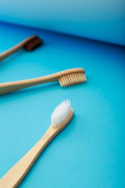Mavi arka plan üzerinde çevre dostu bambu diş fırçası ile Diş bakımı. Sıfır atık ve plastiksiz konsept.