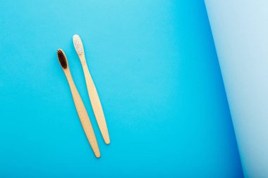 Mavi arka plan üst görünümünde çevre dostu bambu diş fırçası ile diş bakımı. Sıfır atık ve plastiksiz konsept.