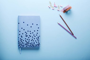 Minimal çalışma alanı: mavi eskiz defteri ve mavi arka plan üzerine kalemler. Üst görünüm , düz yatıyordu.