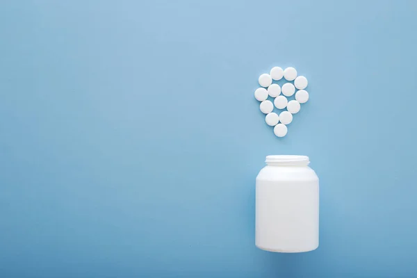 Pastillas de medicina farmacéutica y frasco sobre fondo azul . —  Fotos de Stock