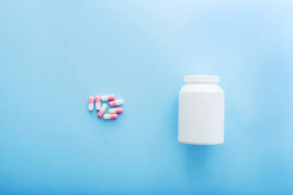 Pilules de médecine pharmaceutique et bouteille sur fond bleu . — Photo