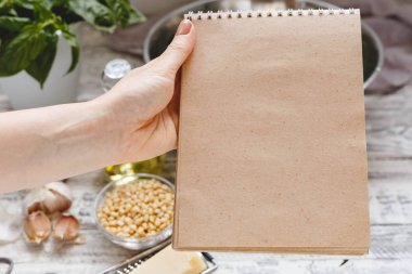 Arka planda malzemelerle geleneksel sos pesto tarifi için Mockup: peynir, fındık, zeytinyağı, fesleğen, sarımsak.