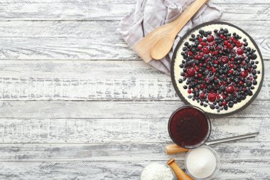 Kiraz, kuş üzümü, böğürtlen, mutfak ve beyaz ahşap masa üzerinde malzemeler ile yaban mersini ile Berry pasta. Cheesecake, kopya alanı ile üst görünüm.