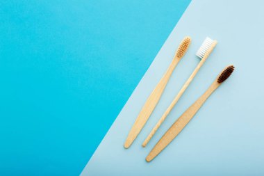 Mavi arka plan üst görünümünde çevre dostu bambu diş fırçası ile diş bakımı. Sıfır atık ve plastiksiz konsept.