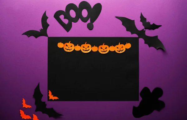 Halloween holiday concept top view. Black spiders, bats, ghost, orange paper Jack O'Lantern, pumpkins on the perple background. Happy Halloween card with copy space. — Stock Photo, Image