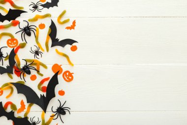 Tatlı şeker, solucanlar, kağıt yarasalar, örümcekler, beyaz ahşap arka plan papalık kabakile Cadılar Bayramı arka plan. Cadılar Bayramı tatil süslemeleri. Düz döşeme, üst görünüm, kopyalama alanı.