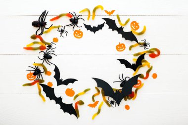 Tatlı şeker, solucanlar, kağıt yarasalar, örümcekler, beyaz ahşap arka plan papalık kabakile Cadılar Bayramı arka plan. Cadılar Bayramı tatil süslemeleri. Düz döşeme, üst görünüm, kopyalama alanı. Çerçeve