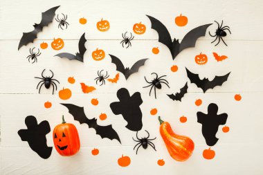 Jack-o'-lanter, kağıt yarasalar, örümcekler, beyaz ahşap arka plan konfeti ile Halloween arka plan. Cadılar Bayramı tatil süslemeleri. Düz yatıyordu, üstten bak. Parti davetiyesi maket, kutlama.