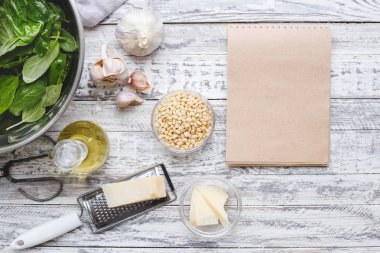 Arka planda malzemelerle geleneksel sos pesto tarifi için Mockup: peynir, fındık, zeytinyağı, fesleğen, sarımsak.