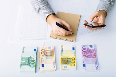 Euro banknotlar istiflenir. Adam muhasebesini yapıyor. Küçük bir işletmede giderlerin dağıtımı. Tasarruf, mevduat, borç verme ve faiz oranı.
