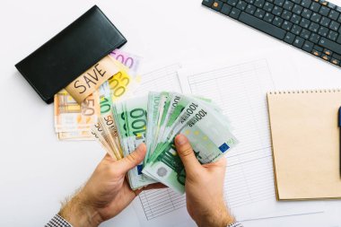 Euro banknotlar istiflenir. Adam muhasebesini yapıyor. Küçük bir işletmede giderlerin dağıtımı. Tasarruf, mevduat, borç verme ve faiz oranı.