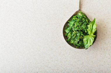 Ev yapımı pesto sosu kaşıkta, fesleğen de mutfakta beyaz masada. Kopyalama alanı olan üst görünüm. Pesto - geleneksel İtalyan sosu fettuccine, Focaccia, pizza, tost, sandviç.