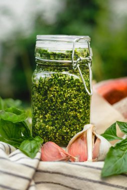 Açık havada piknik sepetinde cam kavanozda pesto. Pesto - geleneksel İtalyan sosu fettuccine, Focaccia, pizza, tost, sandviç, bruschetta.