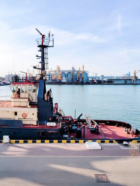 Römorkör limandaki bir rıhtımda, kargo limanında, denizde yüzen kargo vinci, tahıl ambarı asansörleri, liman, botlar ve vinçler. Deniz kargo limanının sanayi manzarası.