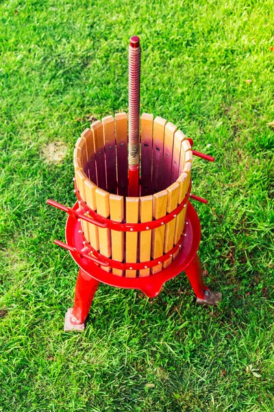Wooden Winepress machine with red details. Crusher on the grass outdoors. Grape harvest. Special equipment for the production of wine, winemaking. Concept of small craft business, home made wine. Autu