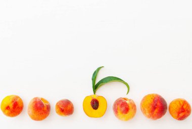 Şeftali ve şeftali, beyaz ahşap arka planda yapraklar. Olgun sulu şeftalili düz kompozisyon fotokopi alanı. Yiyecek ya da meyve suyu için şeftali hasadı. Üst manzara taze organik şeftali meyvesi.