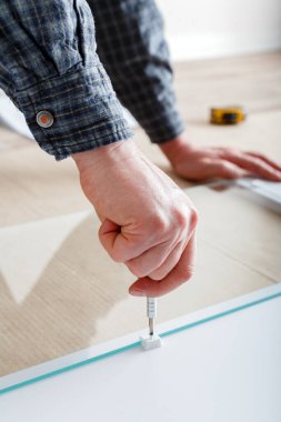 Joiner el aletleri tornavidayla mobilya topluyor. Marangoz beyaz bir mobilya dolabı topluyor. Tornavida kullanarak mobilya montajı. Taşınma, ev dekorasyonu, mobilya tamiri ve yenileme.