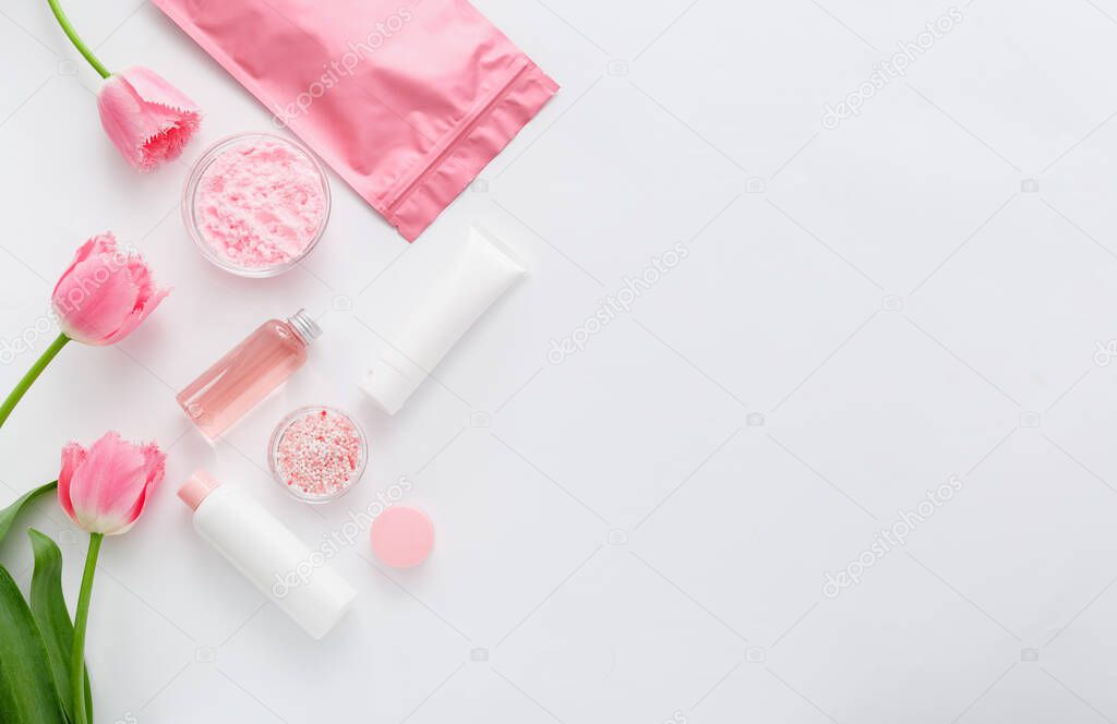 Beauty spa medical skincare bath pink products. Cosmetic bottles, tubes, cream packaging, powder and beads for bathtubs with rose. Cosmetics SPA branding mock up for bath products.Flat lay copy space.