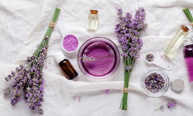 Lavanta yağları, sıvılar, parfümler, beyaz kumaş üzerinde lavanta çiçekleri. Cilt bakımı güzellik ürünleri. Lavanta yağı. Aromaterapi için eczacı bitkileri. Düz, uzun web pankartı