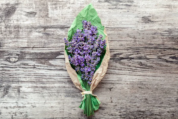 Bouquet of lavender in paper packaging. Fresh lavender flower greeting bouquet on old rustic wooden table. Flatlay french provence style flower blossom. Lavender aromatherapy. Drying lavender flowers.