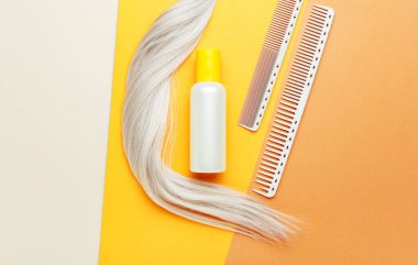 Sarı saç ve tarak bukleli turuncu şampuan şişesi. Kuaför aletleri, kuaförde kuaför malzemeleri, berber dükkanı. Üst görünüm saç kozmetikleri.