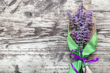 Kağıt ambalajlı lavanta demeti, metin için kopyalama alanı. Taze lavanta çiçeği, eski kırsal ahşap masadaki buketi selamlıyor. Flatlay Fransız Provence tarzı. Lavanta aromaterapisi.
