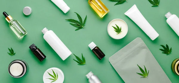 Cam damlası şişesinde kenevir yağı serumu, kenevir yaprağı, nemlendirici krem, serum, losyon, gerekli yağ. Kenevir yaprağı cilt kozmetik ürünü. Düz yeşil arkaplanda uzun afiş deseni yatıyordu.