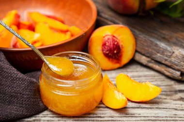 Şeftali dilimleri ve şeftali meyveli cam kavanozda şeftali reçeli. Şeftali reçeli ahşap masada.