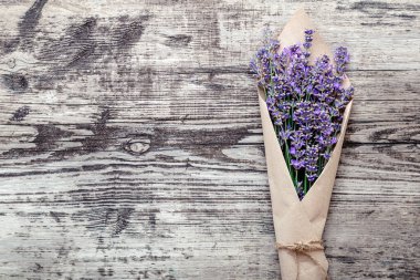 Kağıt ambalajlı lavanta buketi ve metin için fotokopi alanı. Taze lavanta çiçeği, eski kırsal ahşap masadaki buketi selamlıyor. Flatlay Fransız kaynaklı çiçek çiçeği. Lavanta aromalı terapi..