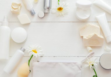 Beyaz kozmetik ürünleri FRAME 'i çiçeklerle ahşap masaya koyun. Güzellik cilt bakımı saç tedavisi kozmetik serum yağı nemlendirici cilt kremi vücut yağı sabun losyonu şampuanı. Düz metin kopyalama alanı.