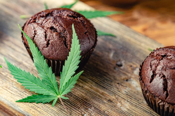 Medical marijuana hemp drugs in food dessert, ganja legalization. Cooking baking chocolate weed muffins. Cupcake with marijuana. Chocolate cupcake muffins with cannabis weed cbd