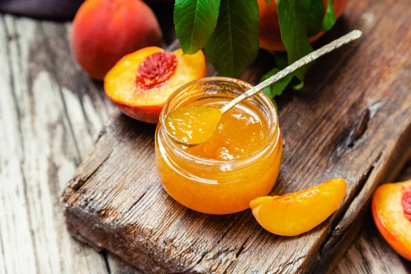 桃のウェッジと全体の桃の果物とガラス瓶の中の桃ジャム 木製のテーブルの上に桃のジャム トップ表示 — ストック写真