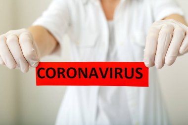 Coronavirus, kırmızı uyarı işareti. Beyaz önlüklü ve eldivenli doktorların elinde Coronavirus yazıyor. Çin Coronavirüsü 2020, Wuhan virüsü, Çin Coronavirüs salgını gribi.