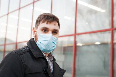 Avrupa koronavirüsü. Yüz hijyenik maskesi takan beyaz bir adamın portresi, açık havada solunum koruma maskesi. Virüs, koronavirüs koruması, hava kirliliği, ekoloji, çevre bilinci