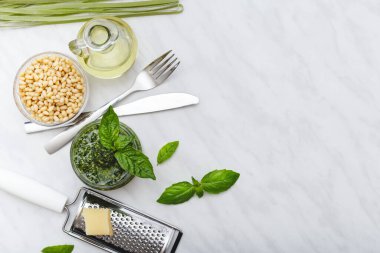 Çam fıstığı, fesleğen, zeytinyağı, parmesan, çatal bıçak takımı, beyaz mermer masada çiğ yeşil fettucine. Pesto fettuccine tarifi. Üst görünüm, metin için kopyalama alanı olan düz uzanma.