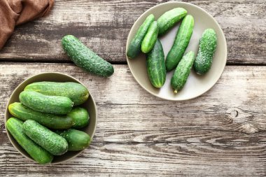 Ahşap bir arka planda, rustik tabaklarda taze çiftlik salatalıkları, kopyalama alanı. Düz yatıyordu