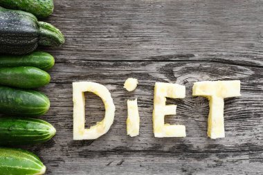 Tahta masadaki sebzelerden yapılmış diyet mektupları, salatalık, kabak çerçevesi, diyet konsepti. Sağlıklı, vejetaryen, çiftlik, doğal, eko. Üst görünüm veya düz uzanma