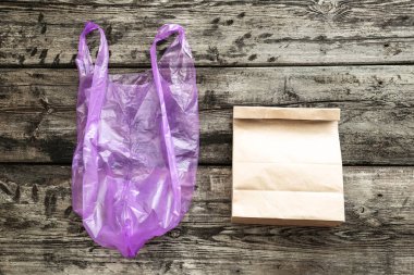Kahverengi boş kağıt torba ve tahta arka planda plastik torba, ambalaj şablonu. Sıfır atık. Uzayı kopyala Reklam alanı. Dünyayı Kurtarma Konsepti, plastik poşet yok.