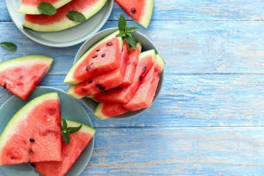Düz kırmızı karpuz dilimleri mavi rustik ahşap arka planda, fotokopi alanı ile birlikte duruyordu. Arka planda karpuz dilimi ve nane şekeri. Üst Manzara. Yaz konsepti