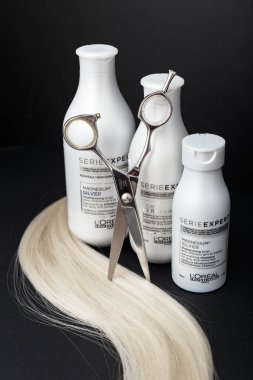 L 'oreal Profesnel Paris Serie Uzmanı Gümüş Saçlı Profesyonel Yapımcılar. Gri beyaz saçlar için Loreal şampuan kremi maskesi. Profesyonel kuaför makası ve siyah arka planda sarı saç tutamı..