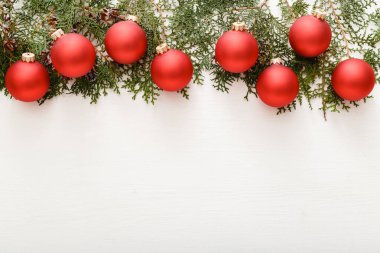 Kırmızı süslemelerden yapılmış Noel kompozisyonu, beyaz ahşap masa zemininde köknar ağacı dalları. Noel, Noel, kış, yeni yıl konsepti. Düz konum, üst görünüm, kopyalama alanı.