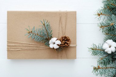Christmas composition made of present,gift decorated with fir tree branches, cotton, bumps on white wooden background, table. Christmas, Xmas, winter, new year, zero waste concept. Flat lay, top view clipart