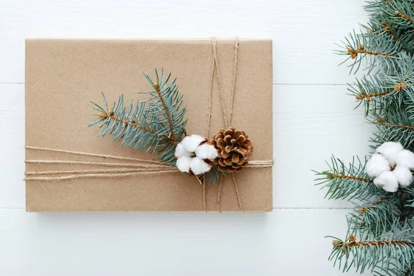 Christmas composition made of present,gift decorated with fir tree branches, cotton, bumps on white wooden background, table. Christmas, Xmas, winter, new year, zero waste concept. Flat lay, top view — Stock Photo, Image