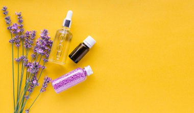 Lavanta cilt kozmetik ürünlerini hazırlayın. Doğal spa güzellik ürünleri sarı arka planda taze lavanta çiçeği otları. Lavanta esaslı yağ serumu krem banyo boncukları. Düz metin kopyalama alanı.