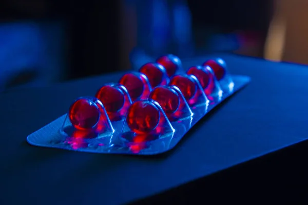 Medicamentos rojos brillantes en cápsulas redondas en placa de embalaje — Foto de Stock