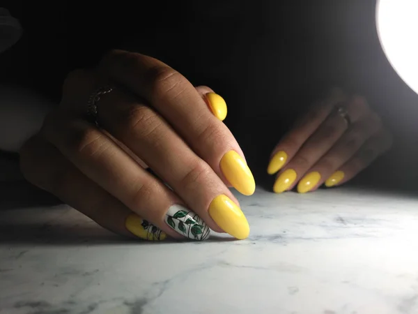 Gel amarelo polonês, manicure com design de galho e folhas verdes em — Fotografia de Stock