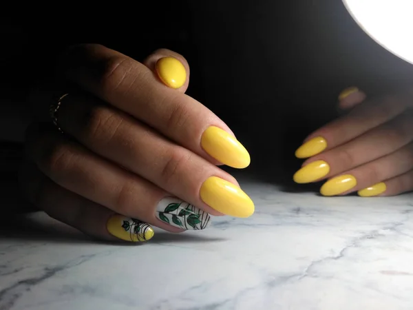 Gele gel Polish, manicure met twig ontwerp en groene bladeren op — Stockfoto