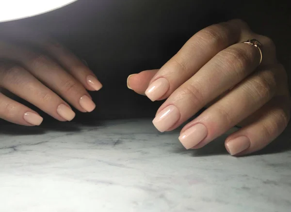 Delicatamente rosa manicure giovane ragazza su uno sfondo scuro — Foto Stock